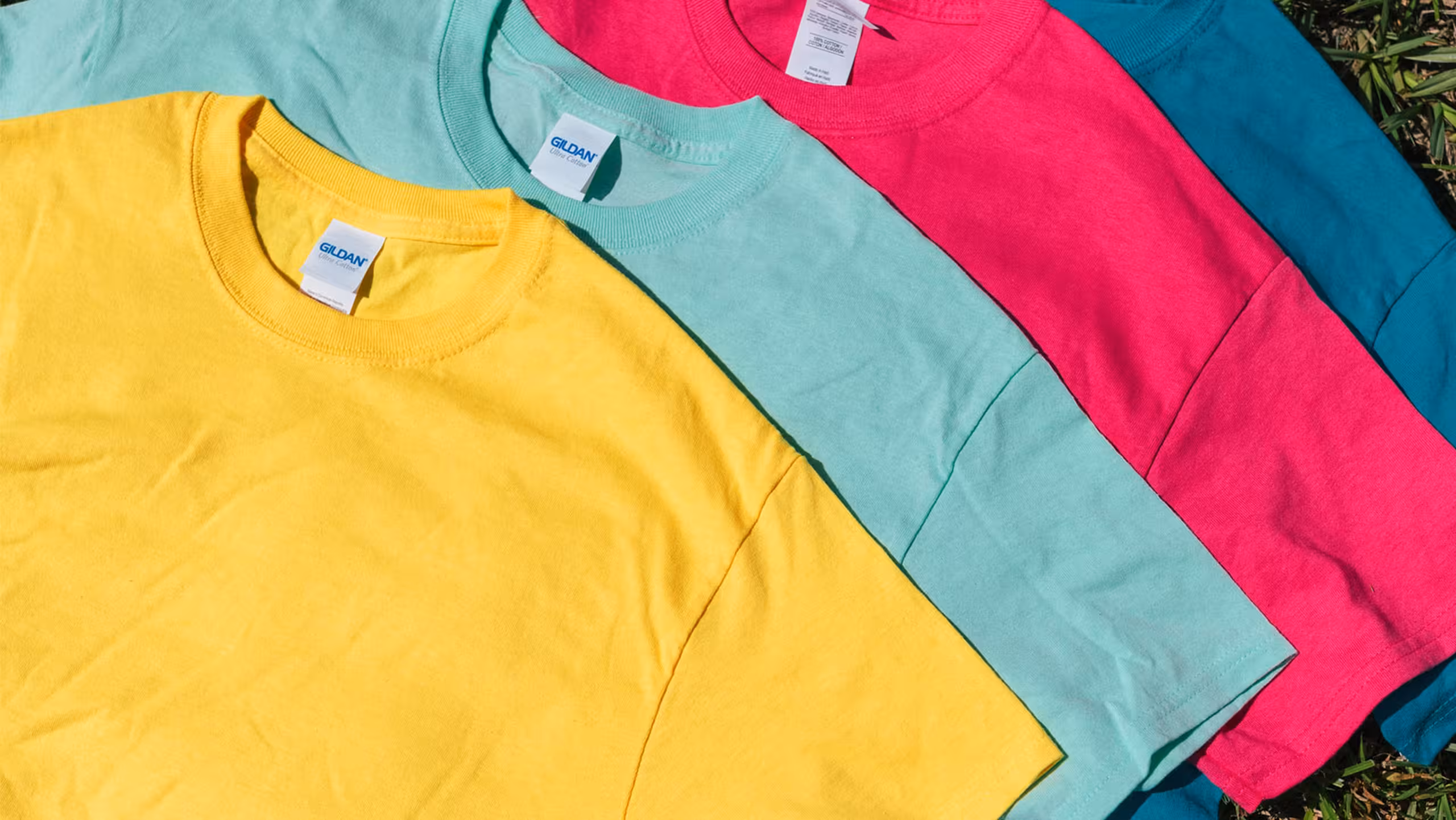 four t-shirts: one bright yellow, one bright green, one bright pink, and one bright blue