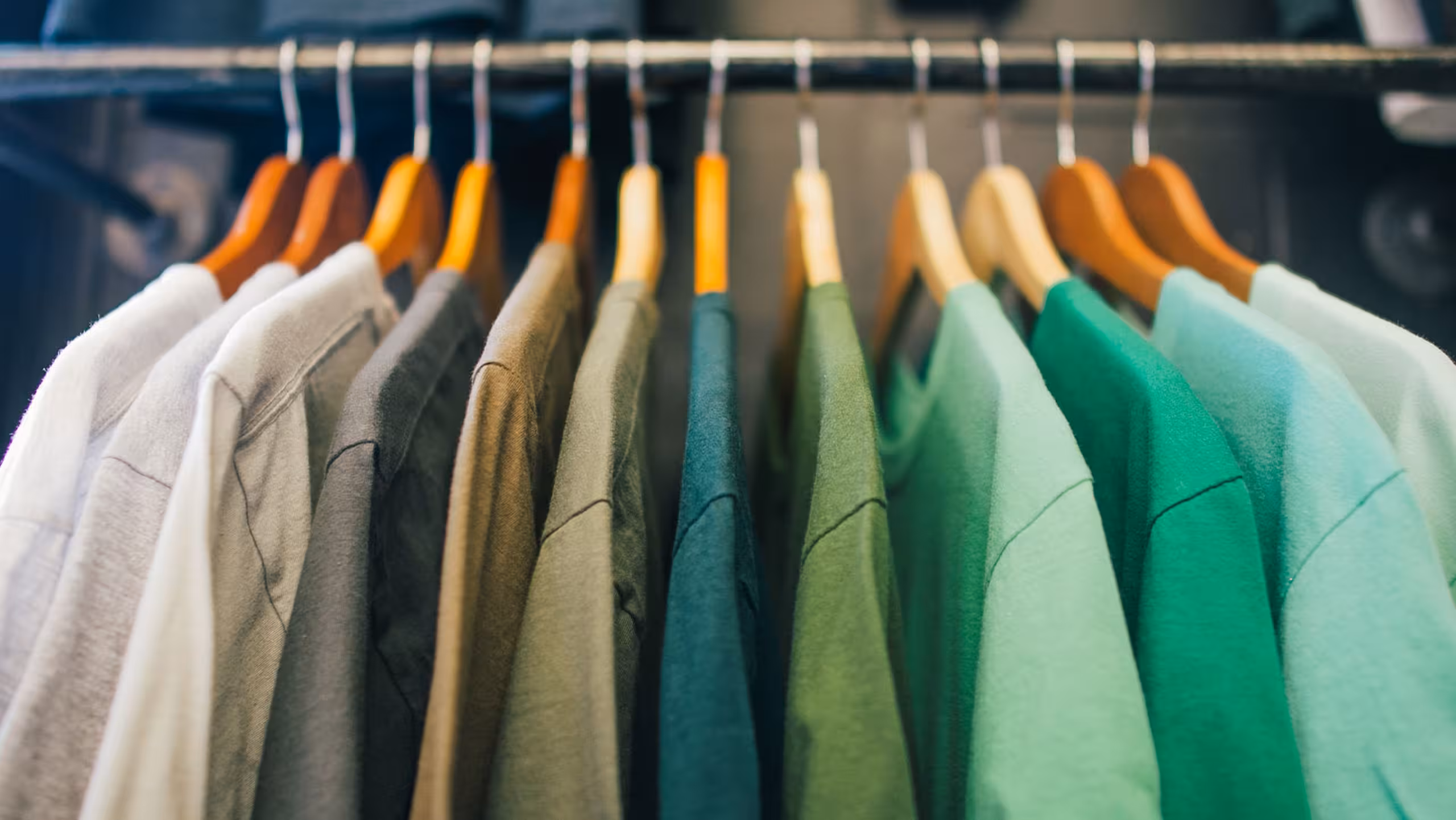 green t-shirts hanging on a clothing rack.