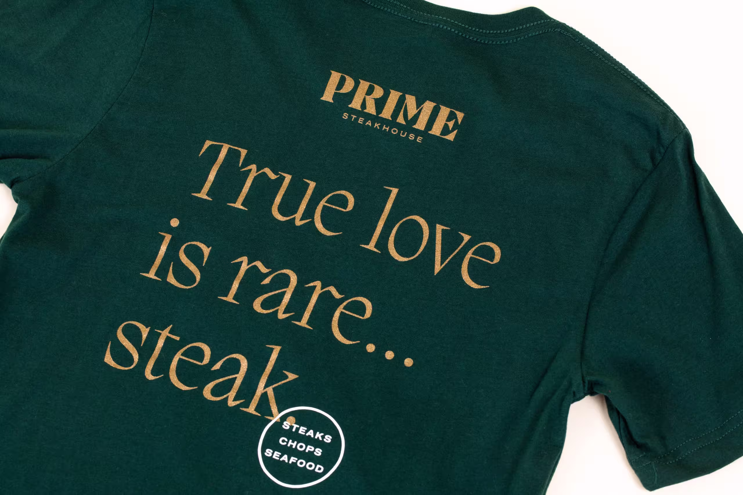 A green shirt with gold metallic ink that says "True love is rare...steak" 