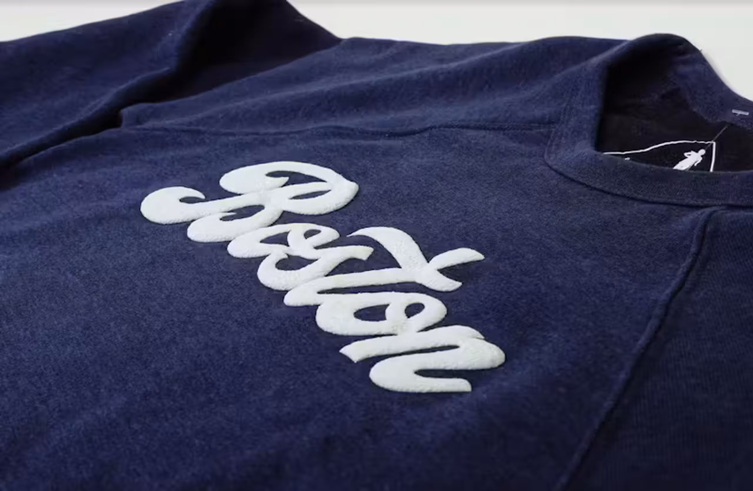 a white word "boston" printed in puff print on a navy t-shirt in a script font