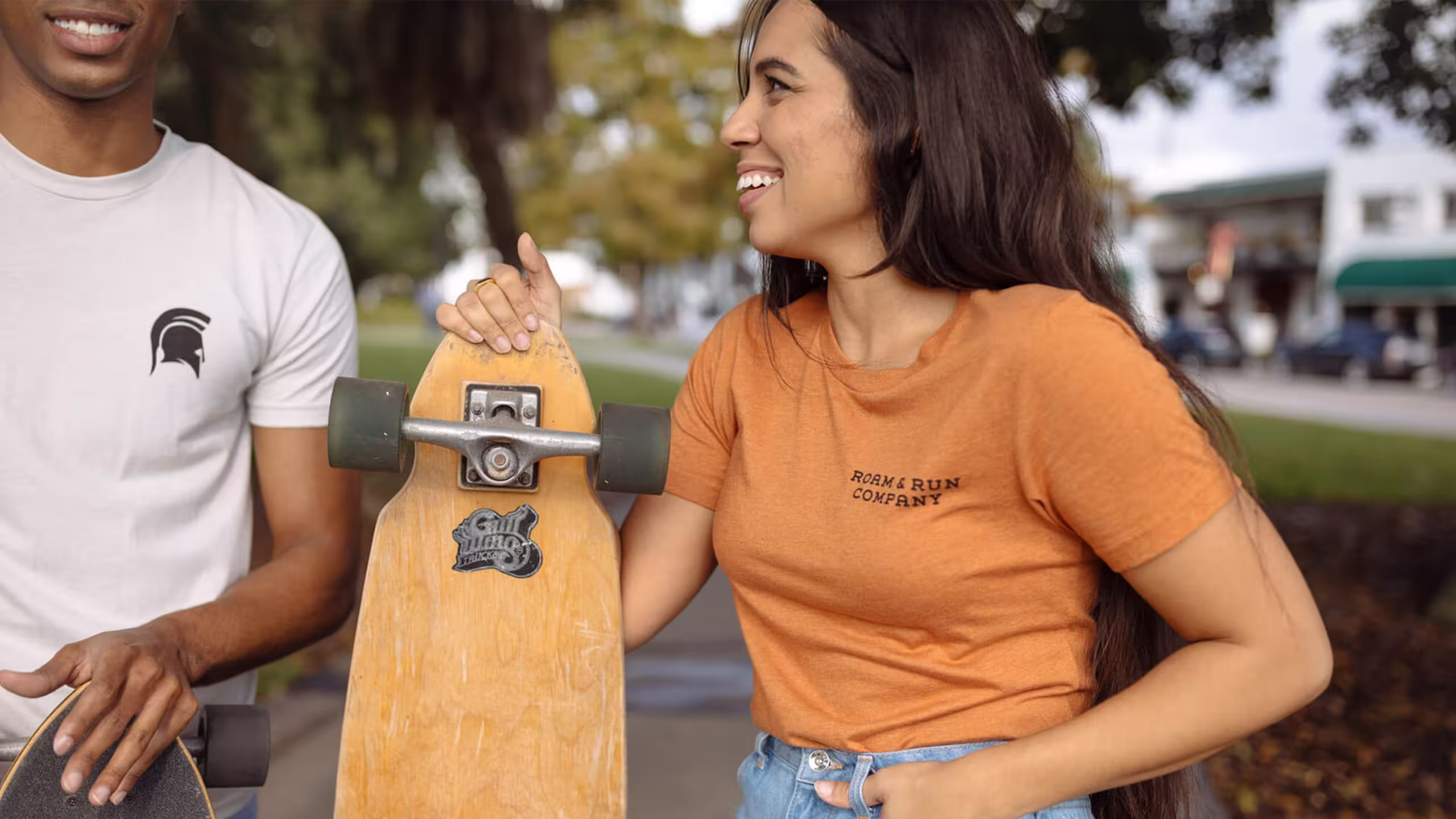 women wearing a orange t-shirt holding a long board skateboard