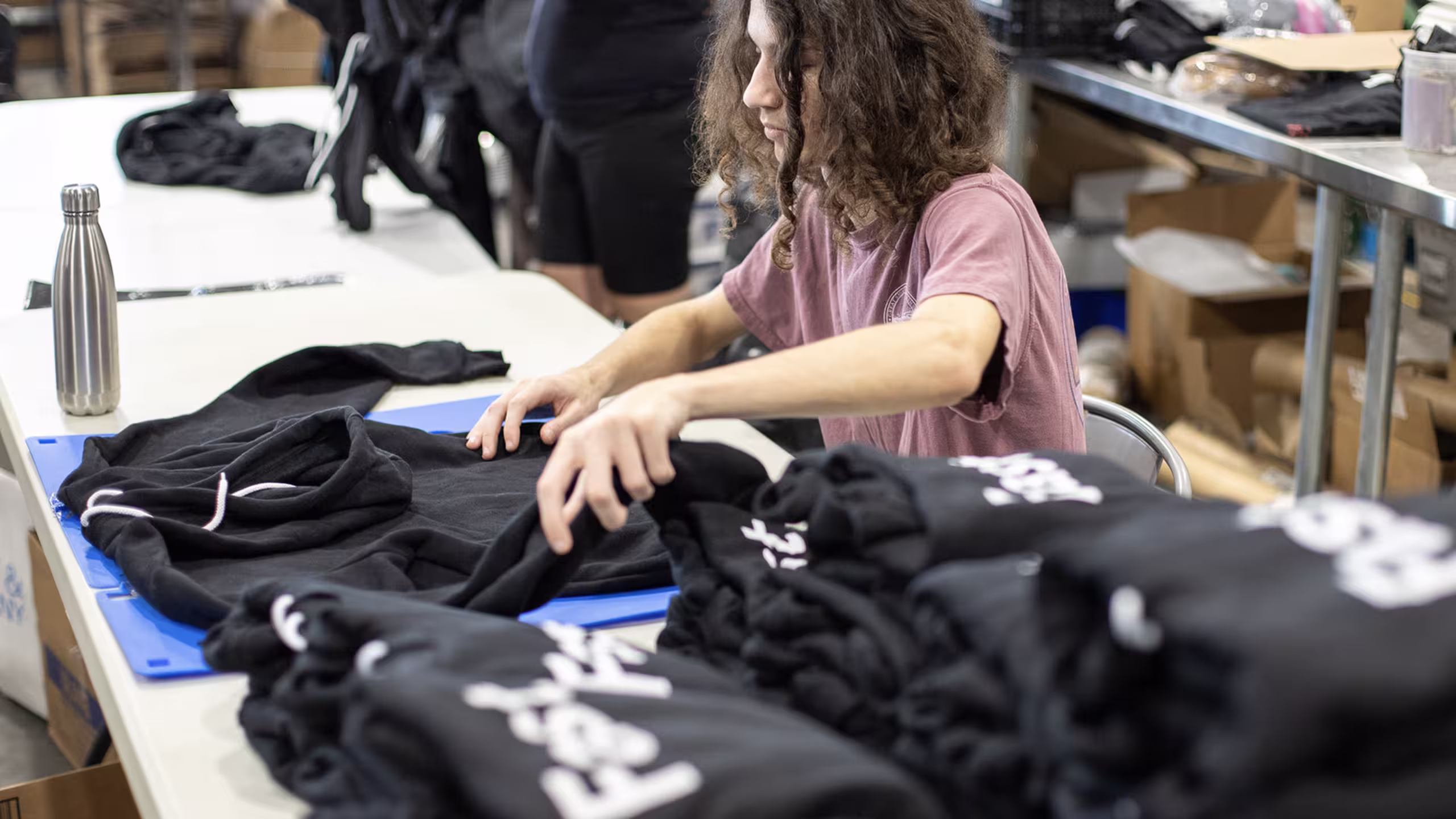 a person folding black hoodies